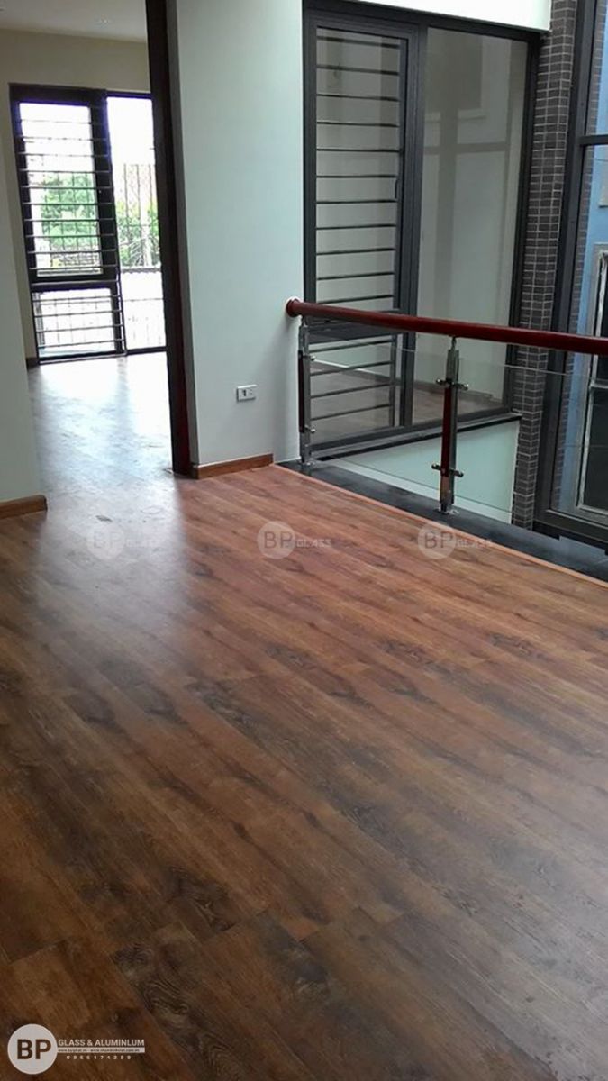 Đoạn cuối lan can kính với tay vịn gỗ nhìn từ không gian tầng thượng